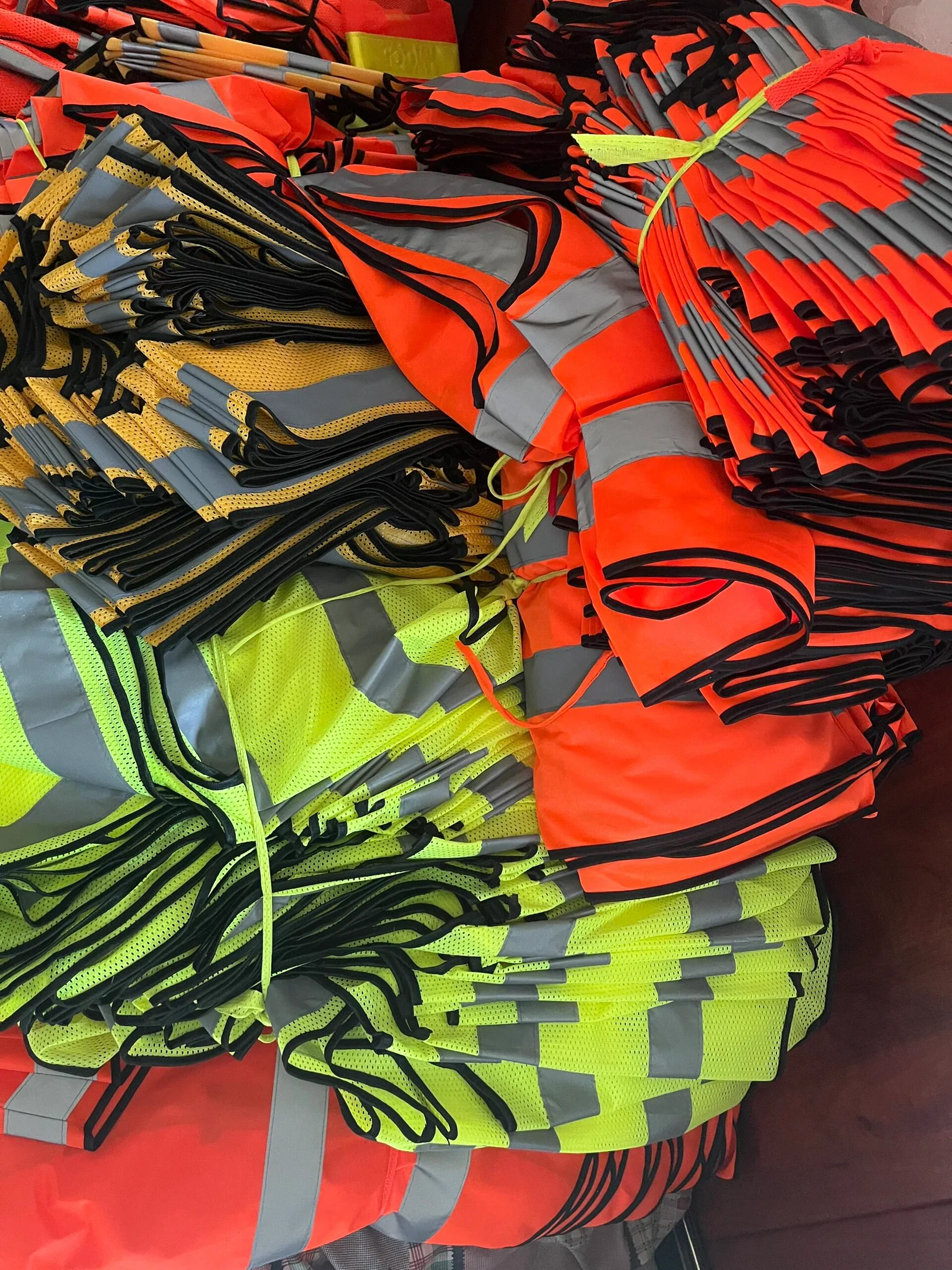 Orange and fluorescent yellow reflective garments organised before final handling