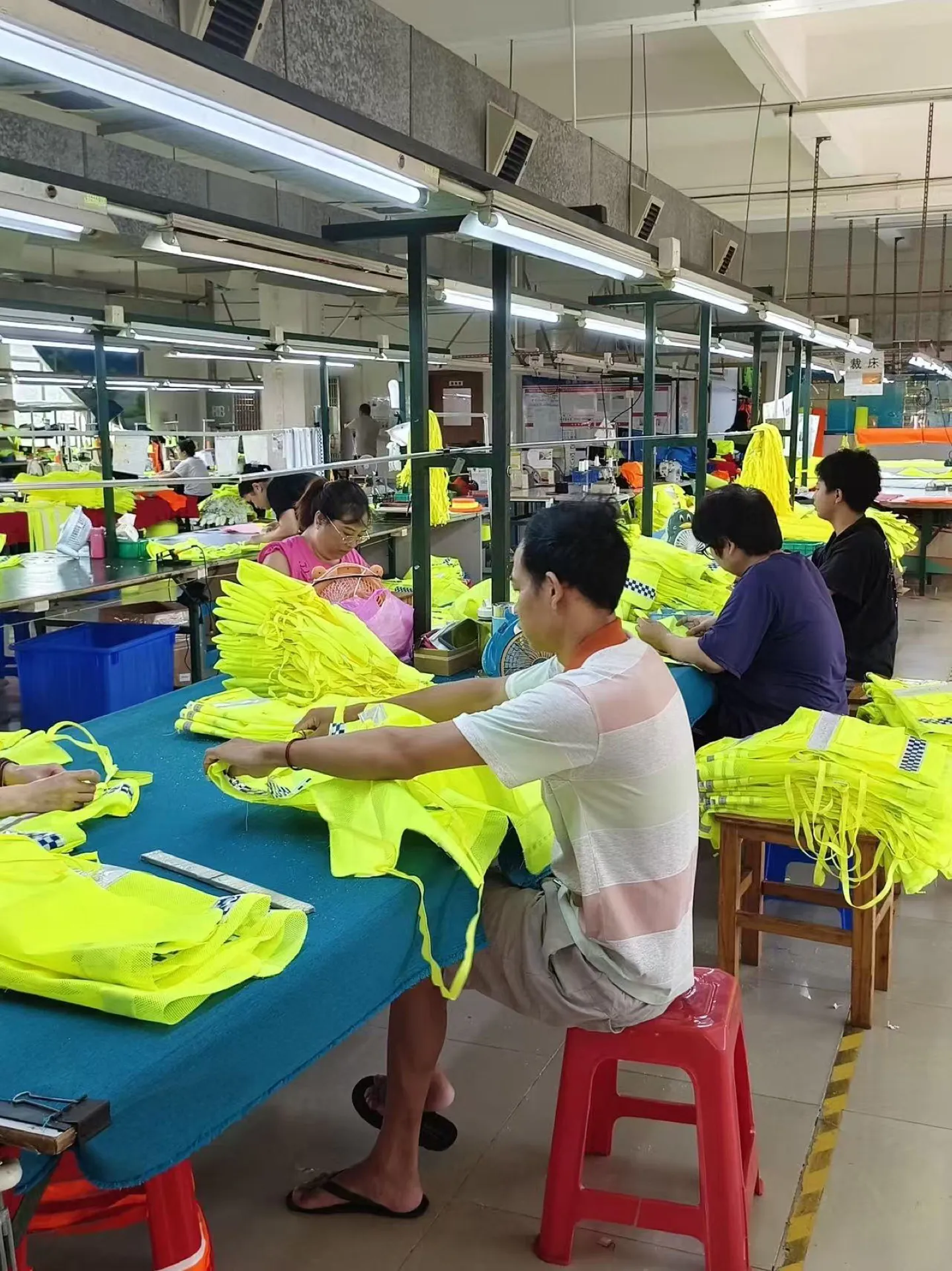 Factory worker organising fluorescent reflective garments during finishing