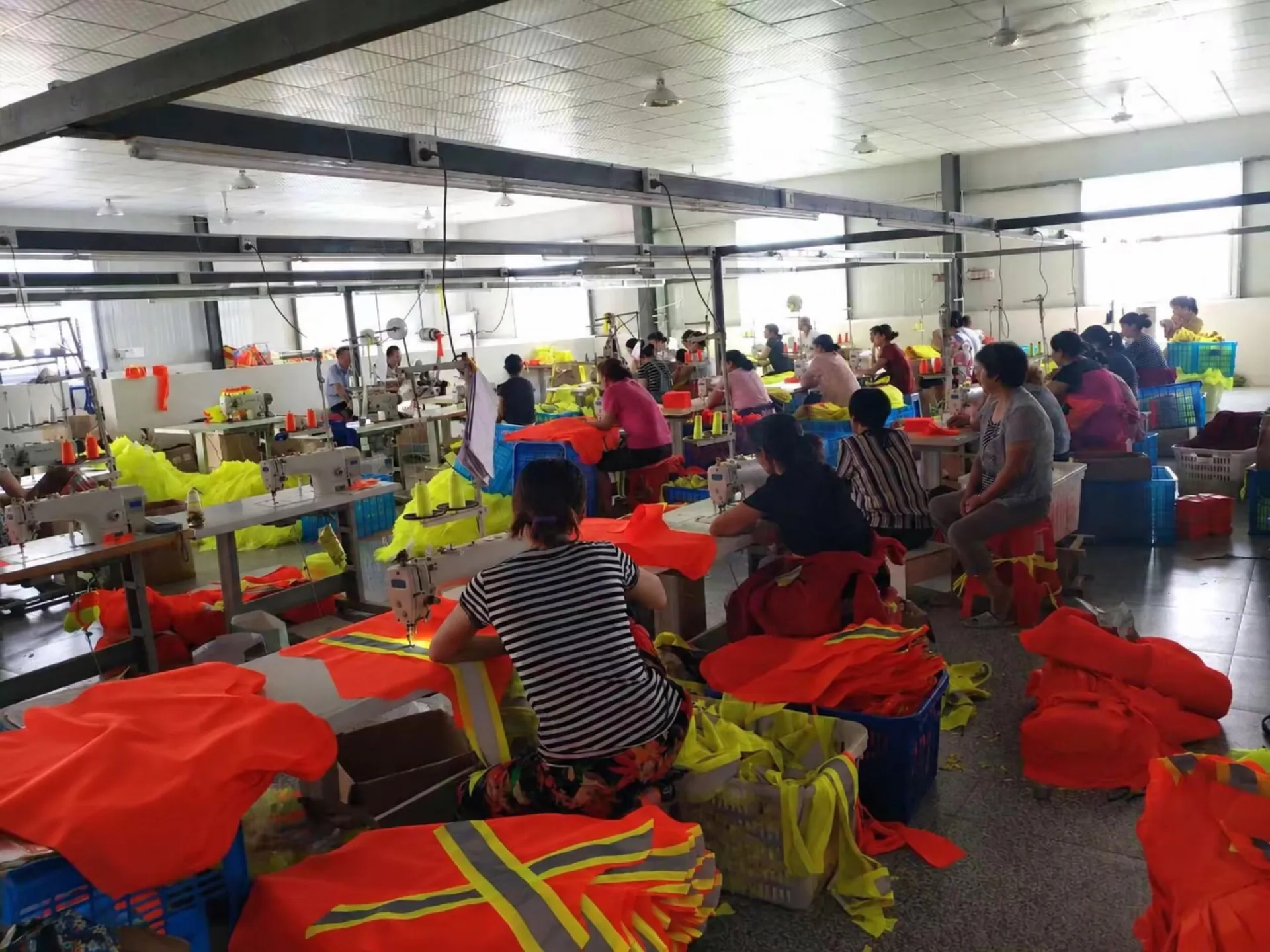 Sewing teams working on orange and fluorescent garments across a production floor