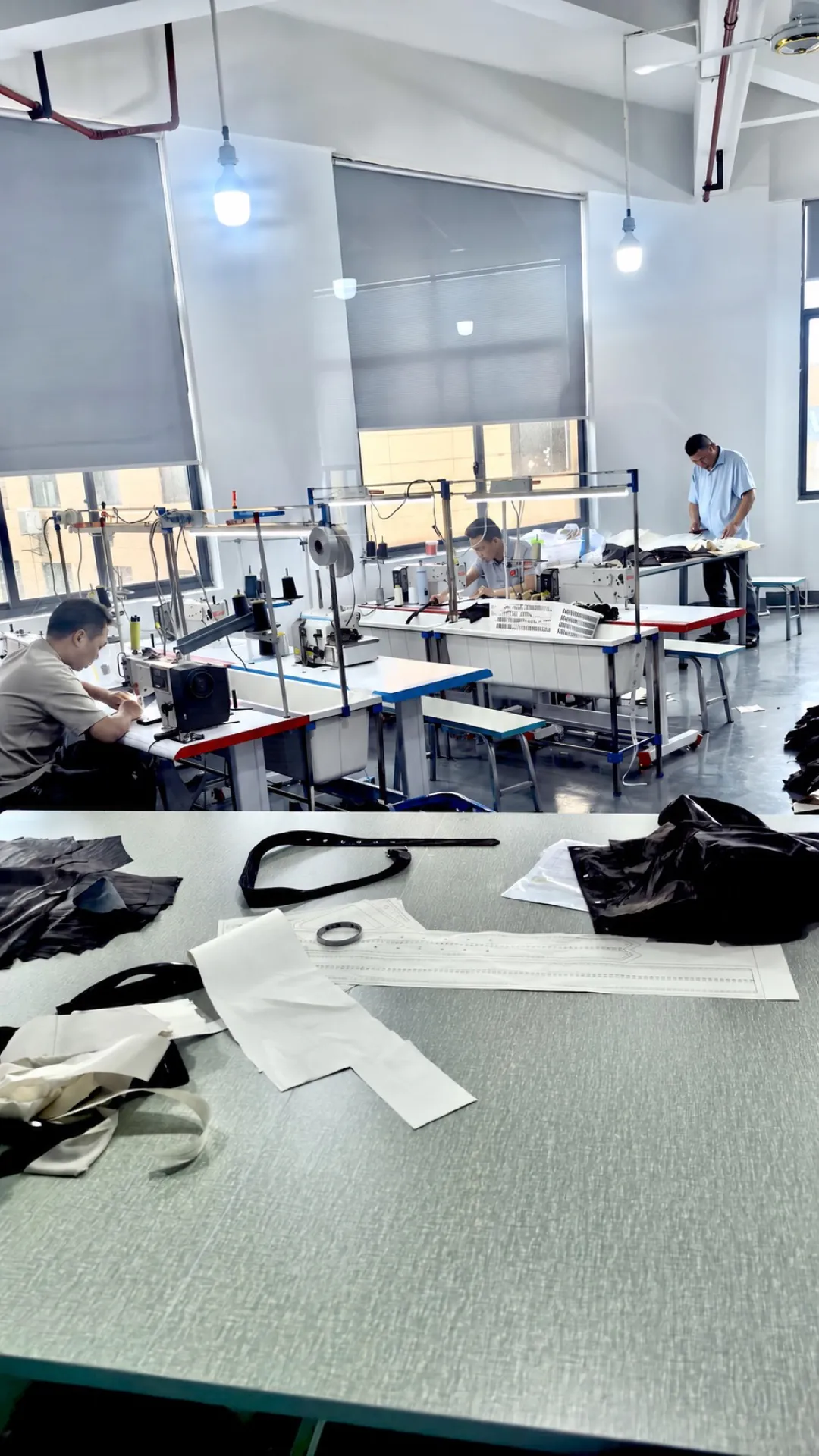 Paper garment pattern on a worktable with operators working behind it